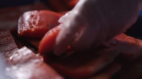 A slice of salmon is lowered into a box with other slices of salmon. Stock Footage 117830201