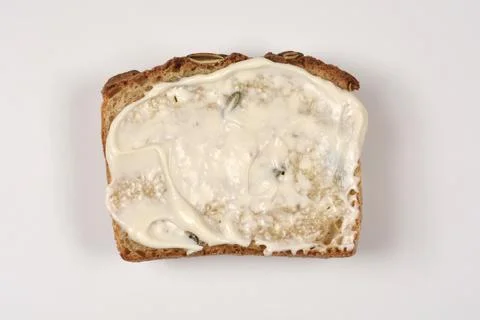 Slice of seed bread with mayonnaise spread top view Fotos Stock
