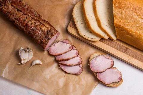 Slice smoked meat or ham, garlic and white wheat bread on brown packing paper Stock Photos