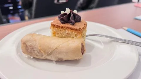 Slice of sponge cake with chocolate cream and fried spring roll Stock Photos
