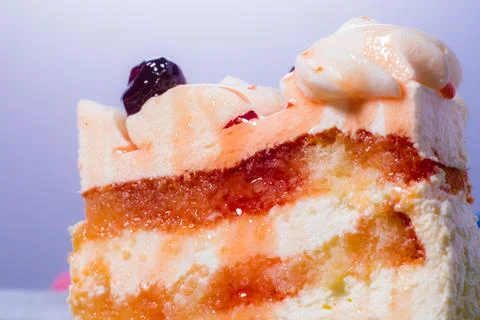 Slice of sponge cake with white cream and red cherry syrup. Stock Photos