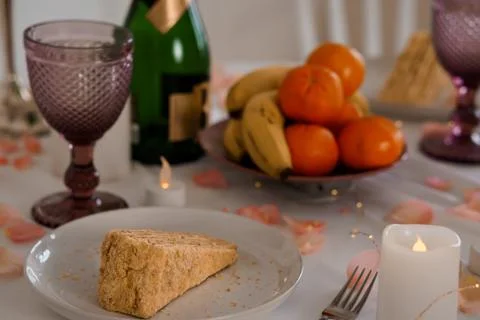 Slice of Sponge Cake on White Plate with Fruit Bowl and Glassware on Table with Stock Photos
