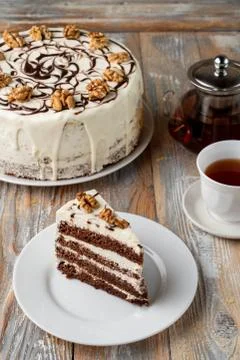 A slice of sponge honey cake with walnut and buttercream on old vintage table Stock Photos