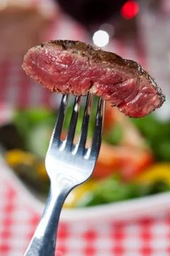 Slice of a steak on a fork over salad Stock Photos