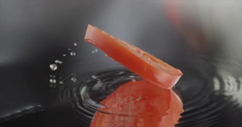 Slice of tomato spinning slides on a mirror surface Stock Footage 197868722