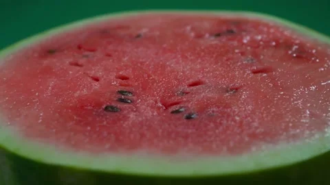 A slice of watermelon on a green background is spinning Stock Footage 159155878