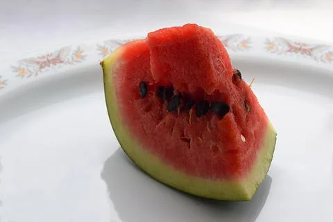 Slice of watermelon on a plate on a white table. Stock Photos
