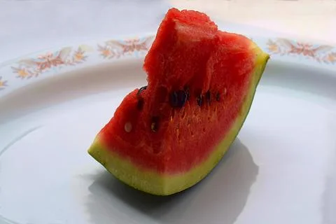 Slice of watermelon on a plate on a white table. Stock Photos