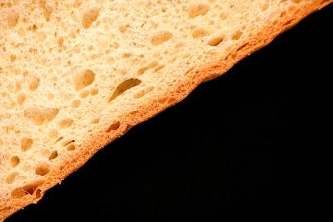 Slice of white bread close up isolated on a black background. rough dappled t Stock Photos