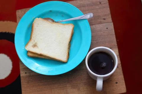 Slice of white bread with a cup of black coffee on wooden table Foto stock