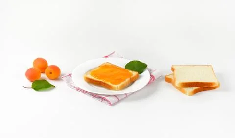 Slice of white bread, one with apricot jam Stock Photos