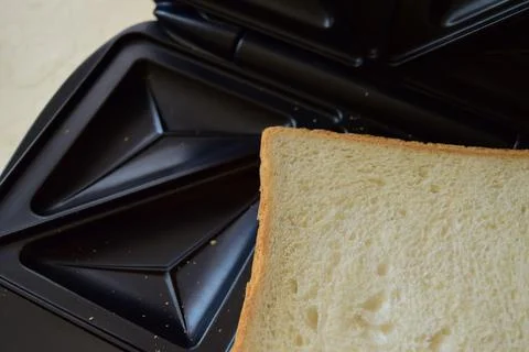 Slice of white bread in a sandwich maker Stock Photos