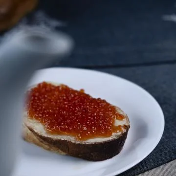 Slice of white buttered bread with red caviar 库存照片