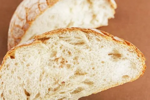 A slice of white fresh crispy bread on a brown background 스톡 사진