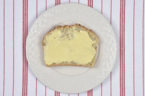 Slice of whole grain bread with spread butter on a plate 写真素材