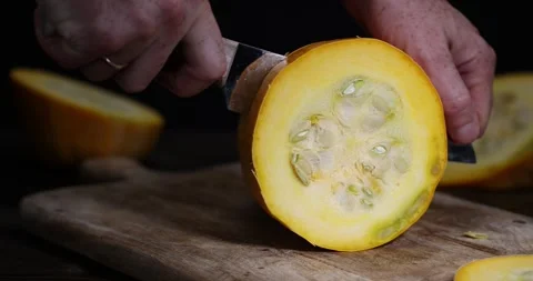 Slice yellow ripe pumpkin or zucchini, slicing ripe zucchini on a black cooking Stock Footage 305675372