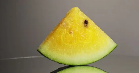 A slice of yellow watermelon rotates 360 degrees on a gray background Stock Footage 152762897