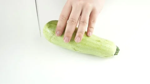 Slice the zucchini with a kitchen knife.Fresh vegetables on a white table. Stock-Footage 136284934