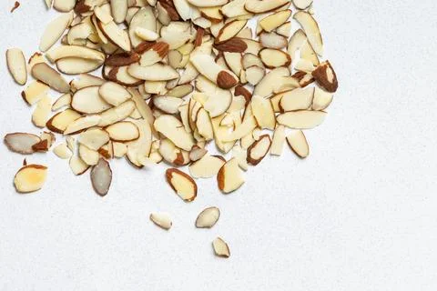 Sliced almonds scattered on a light surface in a kitchen setting Stock Photos