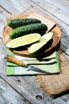 Sliced and whole cucumbers (Cucumis sativus) with knife on chopping board Stock Photos