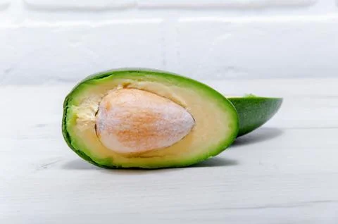 Sliced avocado with bone closeup on a light wooden table. Healthy eating Very Stock Photos
