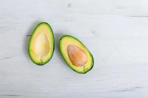 Sliced avocado with bone closeup on a light wooden table. Healthy eating Very Stock Photos