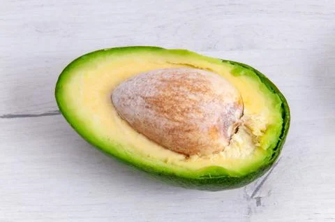 Sliced avocado with bone closeup on a light wooden table. Healthy eating Very Stock Photos