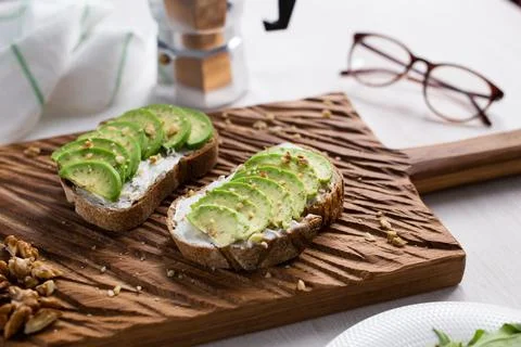 Sliced avocado on toast bread with nuts. Breakfast and healthy food concept. Stock Photos