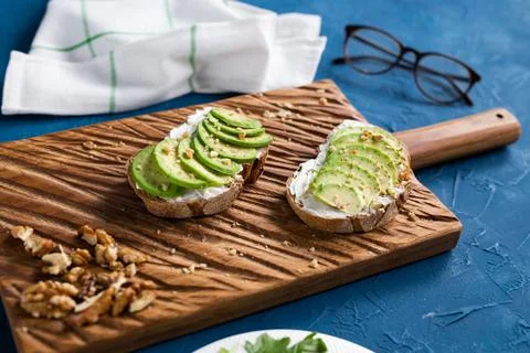 Sliced avocado on toast bread with nuts. Breakfast and healthy food concept. Stock Photos
