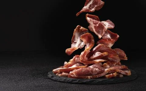 Sliced bacon on black background, raw ham strips Stock Photos