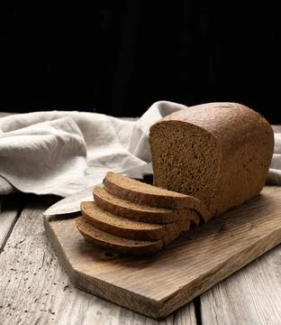 Sliced baked rectangular rye flour bread on brown board, healthy food slic... Stock Photos