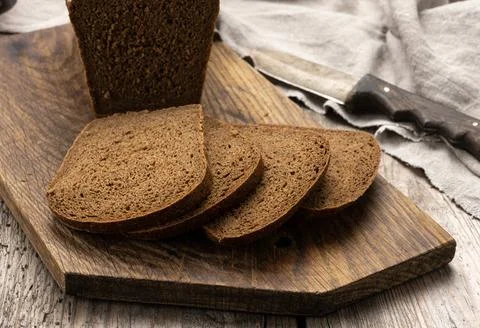 Sliced baked rectangular rye flour bread on brown board, healthy food slic... Stock Photos