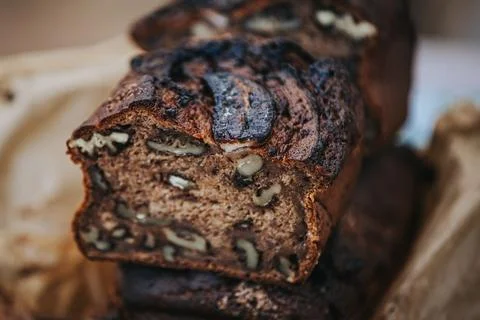Sliced banana bread with walnuts displayed on a rustic wooden surface, show.. Stock Photos