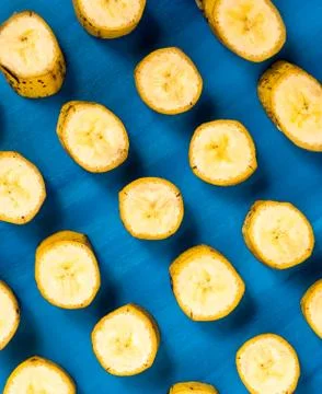 Sliced banana pattern on blue background, wooden table. 库存照片