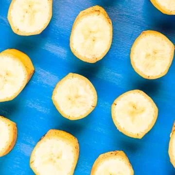 Sliced banana pattern on blue background, wooden table. Stock Photos