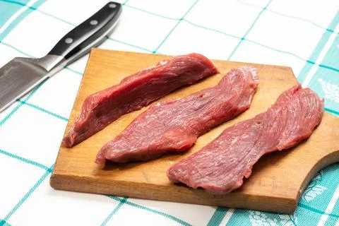Sliced beef meat on the kitchen board with knife in the background Stock Photos