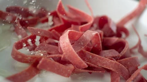 Sliced ​​beef salami are thrown into the oily pan in slow motion. Stock Footage 132350765