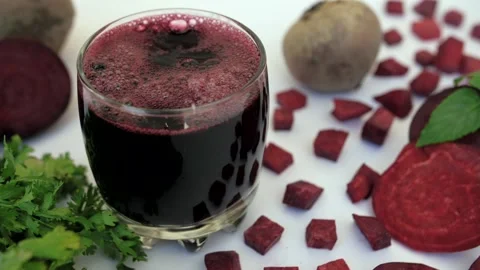 Sliced beetroot falling in a glass of beverage kept against a white background Stock Footage 155771575