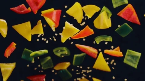 Sliced bell peppers with diced and triangles are tossed into the air with seeds Video stock 111643064