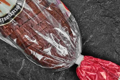 Sliced black rye bread in plastic bag on dark background Stock Photos