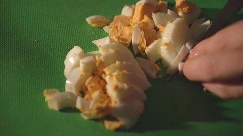 Sliced boiled egg on green cutting board with hand in frame Stock Footage 312767164