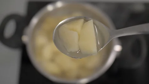 Sliced boiled potatoes in a tablespoon on a background of a potato pan. 4k. Stock Footage 114703833