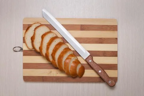 Sliced bread on breadboard and knife Stock Photos