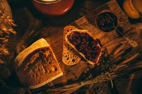 Sliced ??bread with jam in the light of candles on a wooden board. Rustic atm Stock Photos