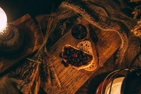 Sliced ??bread with jam in the light of candles on a wooden board. Rustic atm Stock Photos