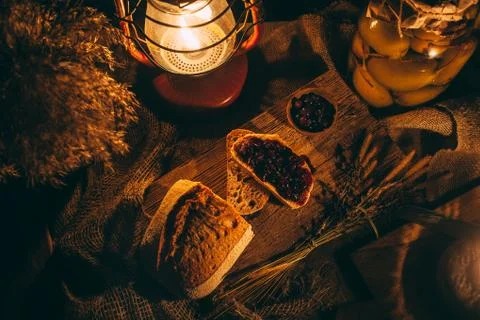 Sliced ??bread with jam in the light of candles on a wooden board. Rustic atm Stock Photos