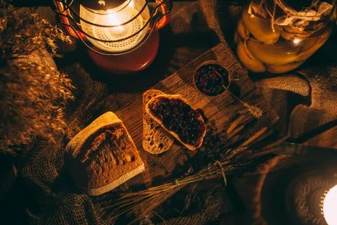 Sliced ??bread with jam in the light of candles on a wooden board. Rustic atm Stock Photos