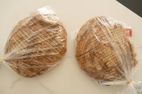 Sliced Bread Loaves Wrapped in Plastic on a Table Foto stock