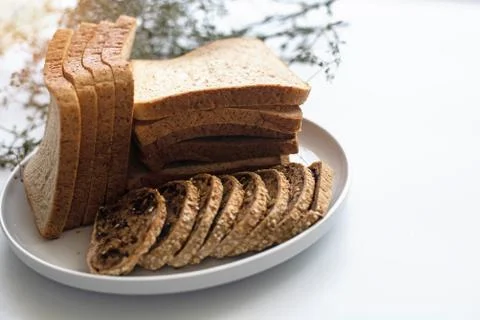 The sliced bread put in white dish,on white desk,blurry light around. Stock Photos