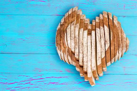 Sliced bread shaped as heart on old blue table Stock Photos
